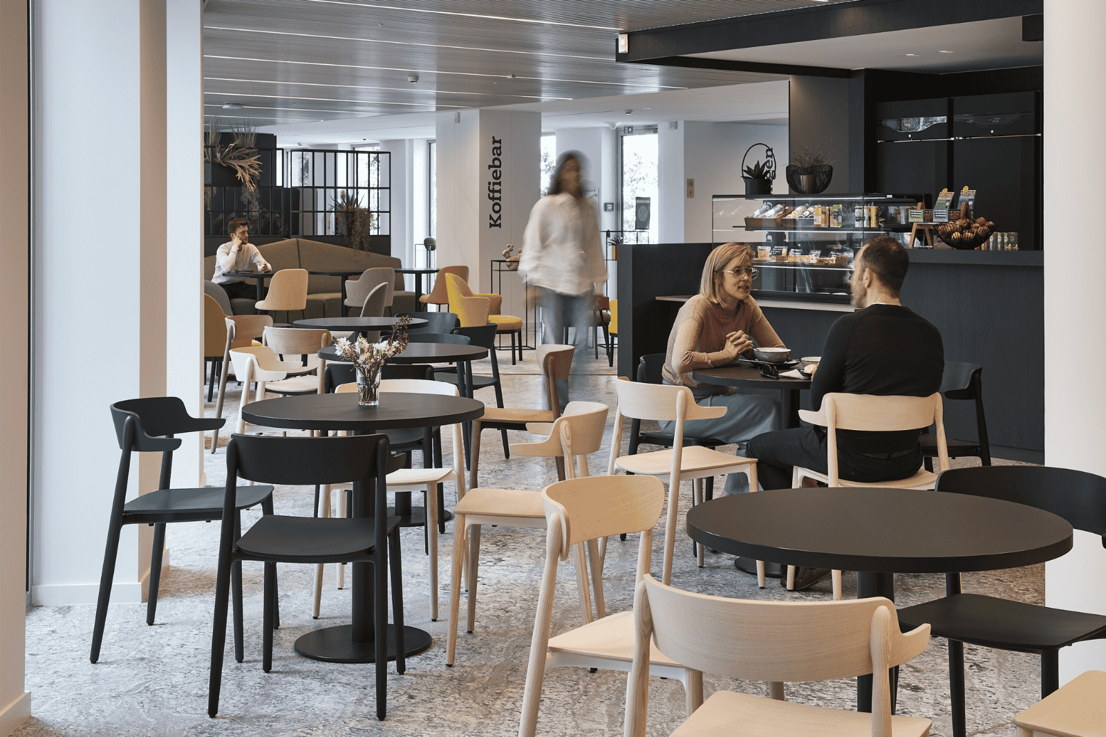 Bedrijfskantine met koffiebaar en mix van lichte en donkere stoelen