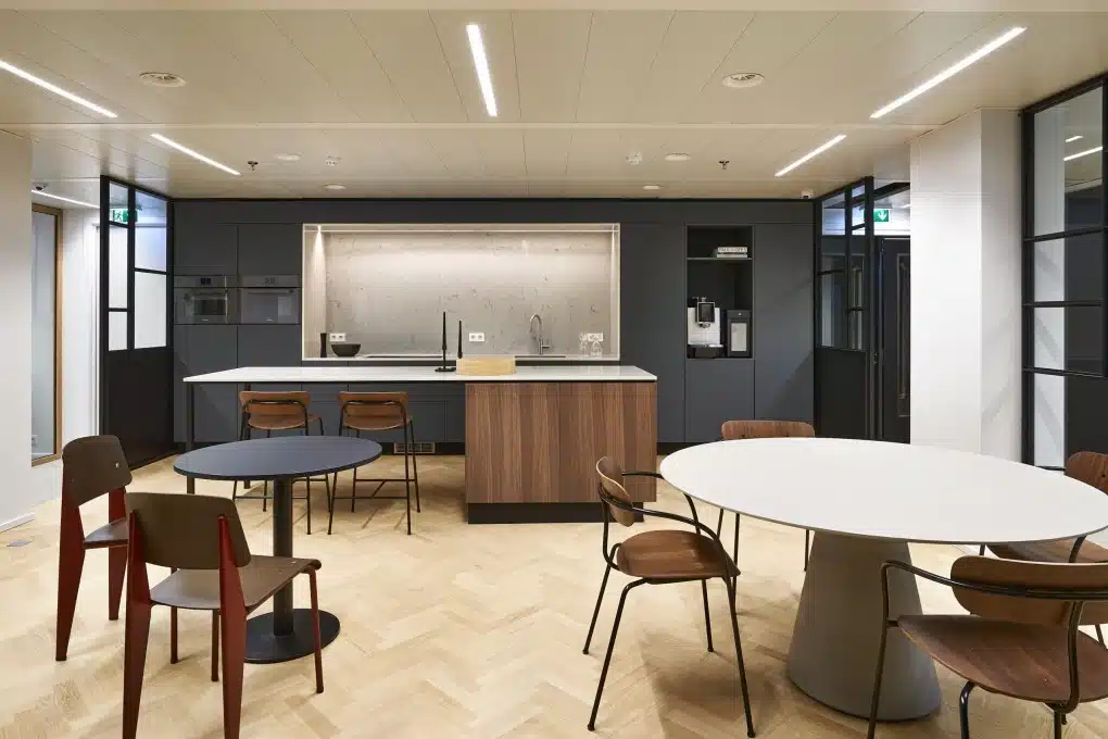 Modern ingerichte kantine met houten vloer, strakke keuken en zitgedeelte voor medewerkers en klanten
