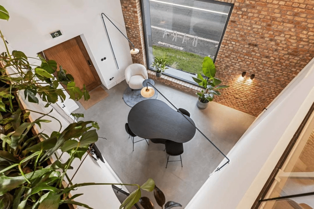 Coin salon avec table ronde et beaucoup de lumière naturelle dans l'espace de coworking de Barn Coworking