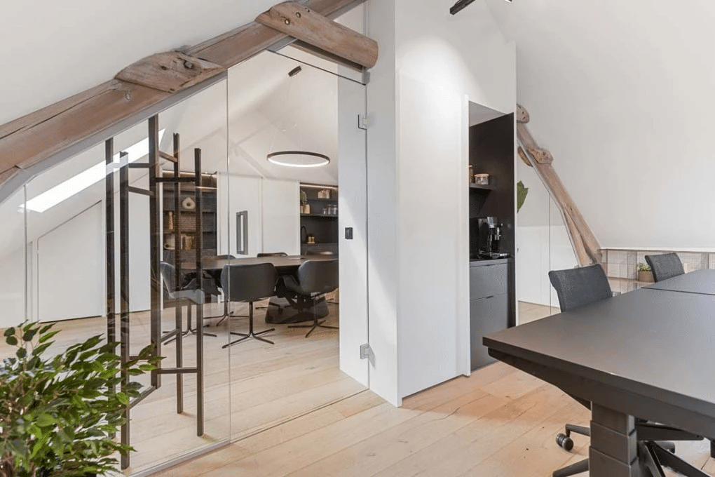 Salle de réunion avec des murs en verre et des accents en bois dans l'espace de coworking Barn Coworking, aménagée par Buro Project