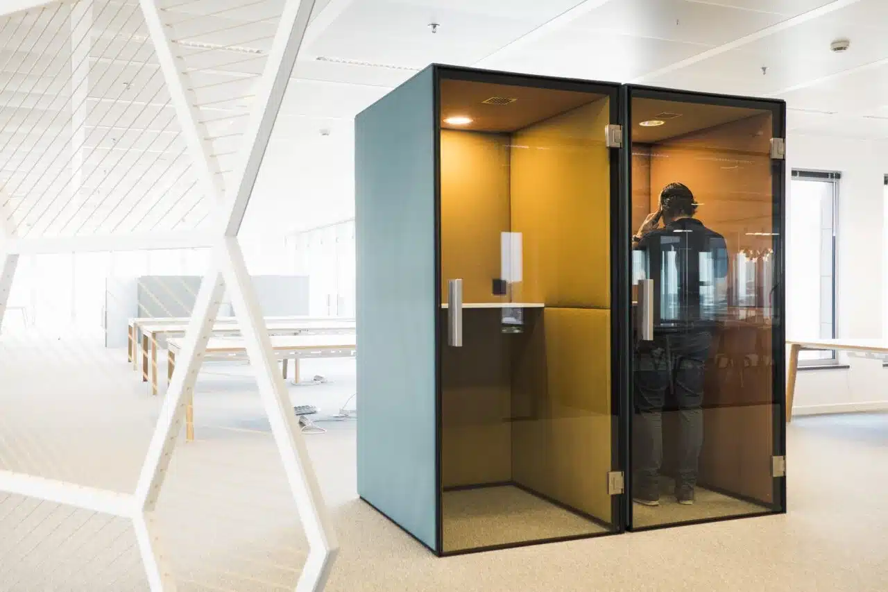 Une cabine téléphonique dans un espace de travail flexible montre comment des accords clairs sur les zones de silence assurent la tranquillité et l'intimité