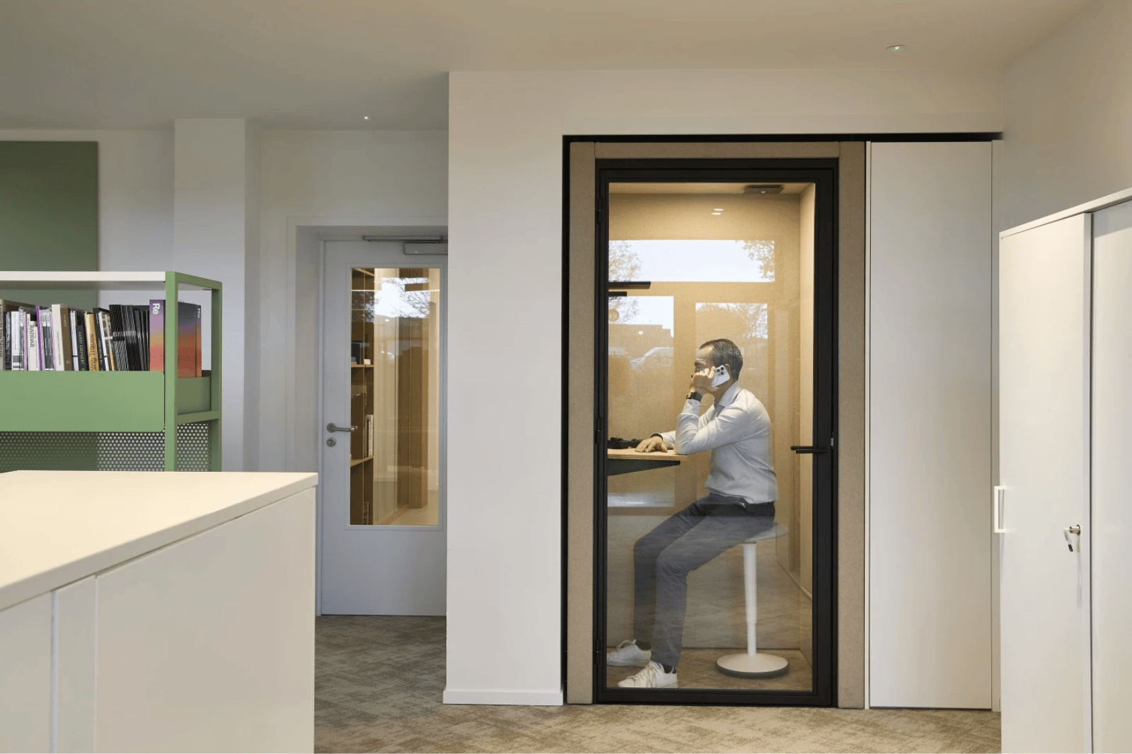 Un employé passe un appel téléphonique dans une cabine téléphonique silencieuse d'un espace de travail flexible