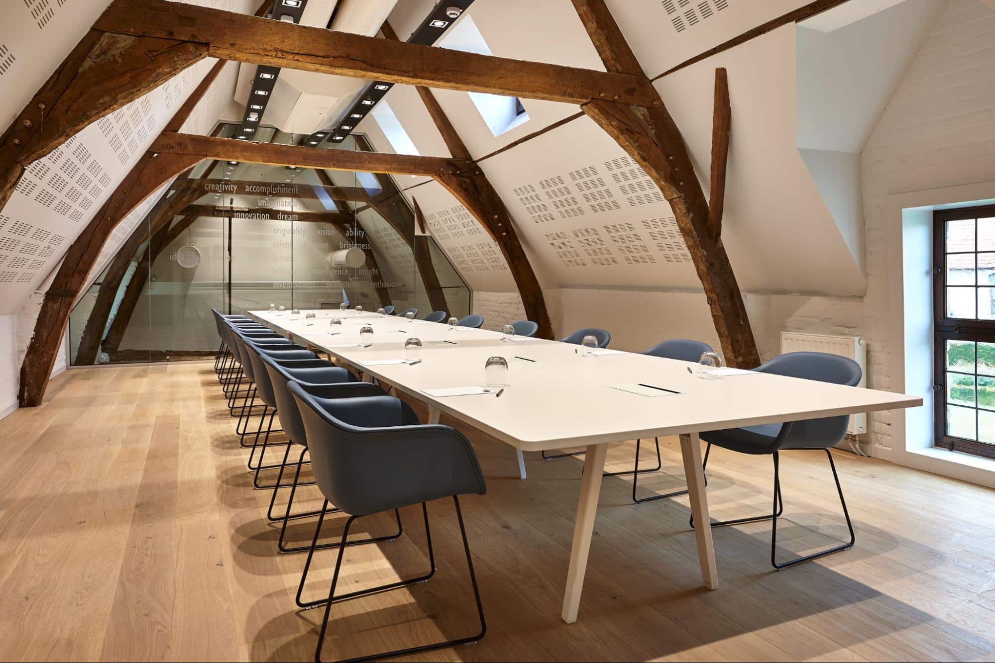 Salle de réunion avec longue table et chaises modernes sous poutres en bois authentiques dans une université