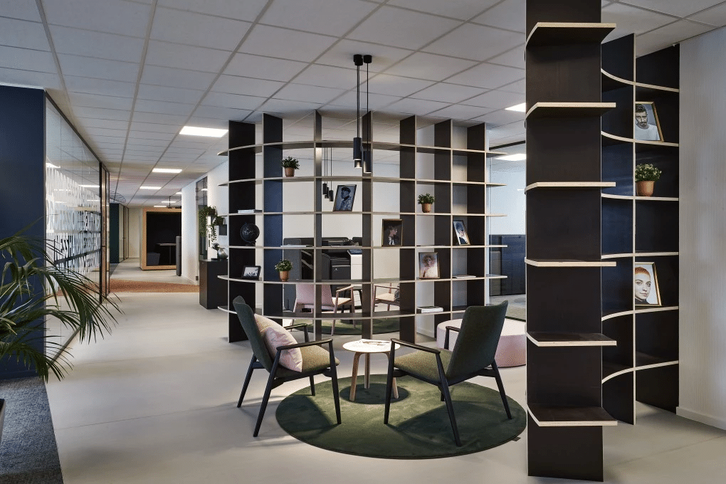 Moderne kantoorinrichting met open werkruimte, stijlvolle roomdivider en gezellige zithoek voor informele meetings.