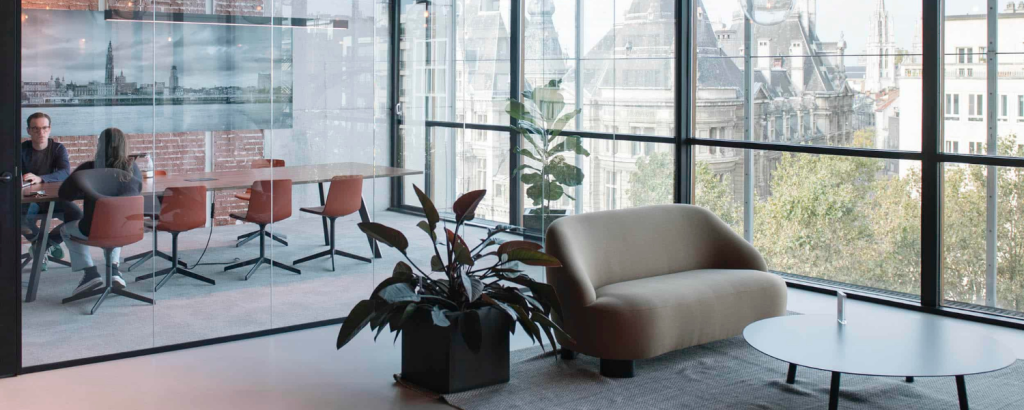Moderne kantoorruimte met lounge zetel, vergadertafel en stoelen achter glazen wand