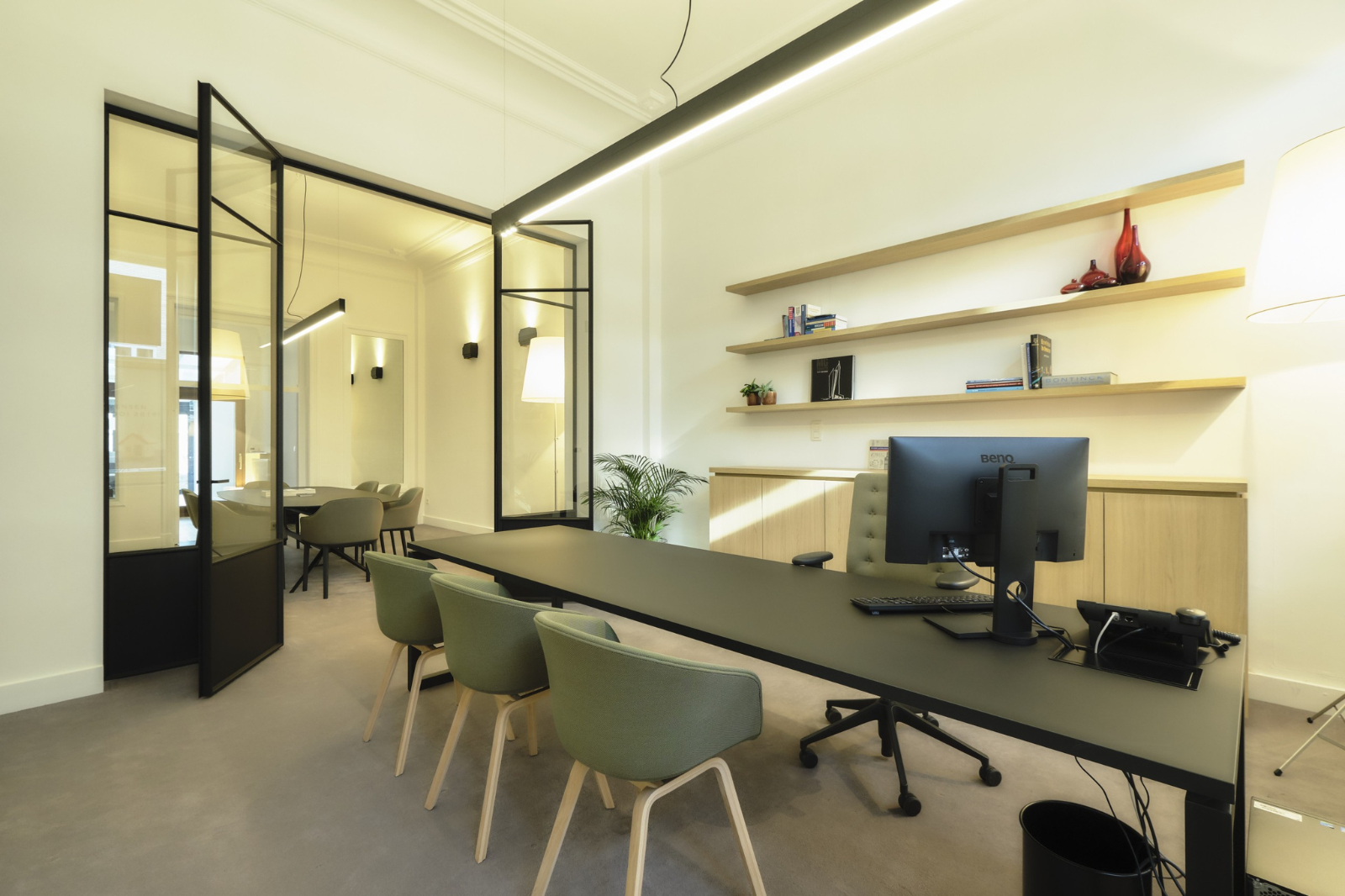 Petit bureau lumineux avec des cloisons vitrées et un éclairage au plafond qui agrandit optiquement l’espace.
