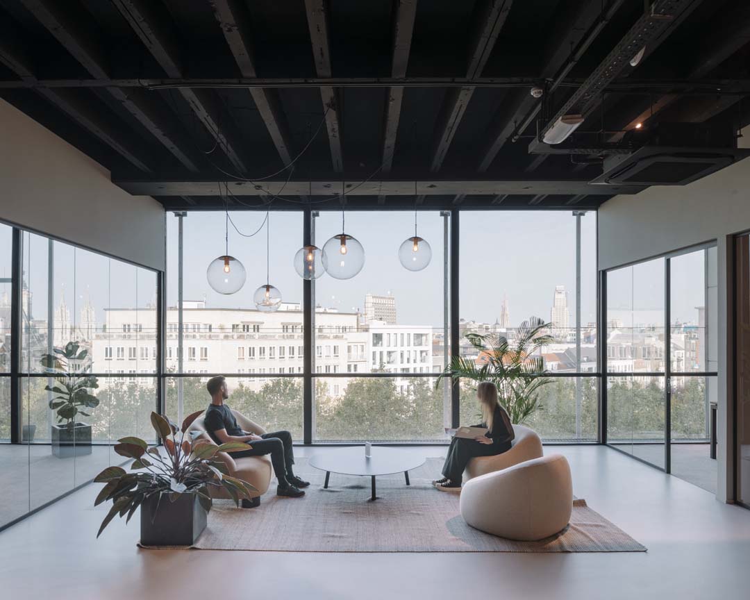 Werkplek van de toekomst met informele loungehoek en panoramisch zicht als ontmoetingsplek voor medewerkers
