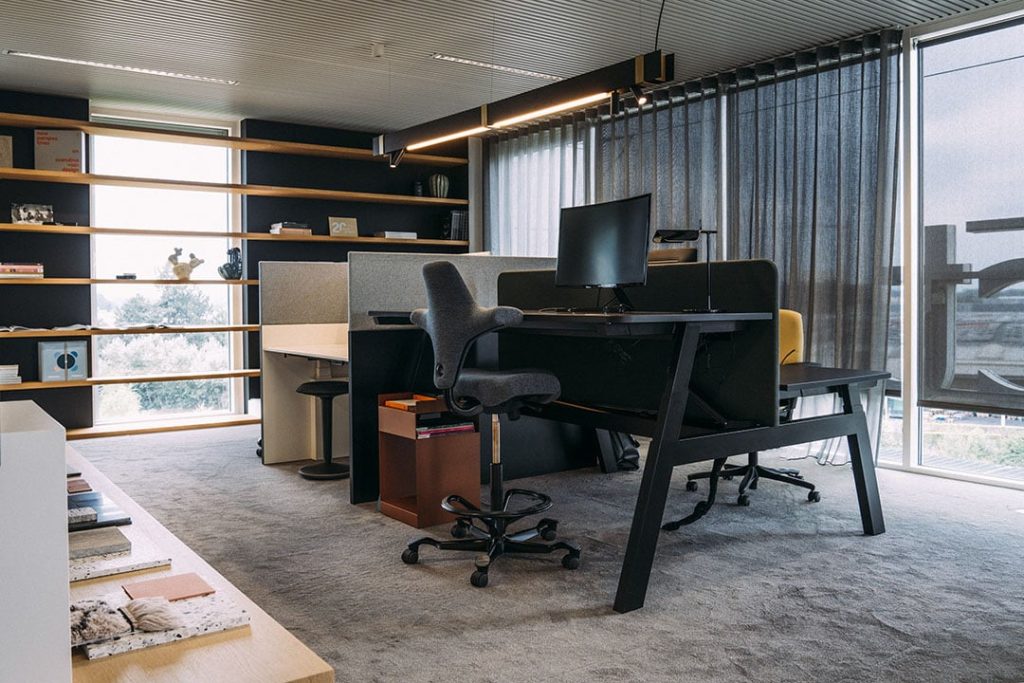 Ergonomische werkplek met zit-sta bureau, ergonomische kruk en akoestisch bureauscherm.
