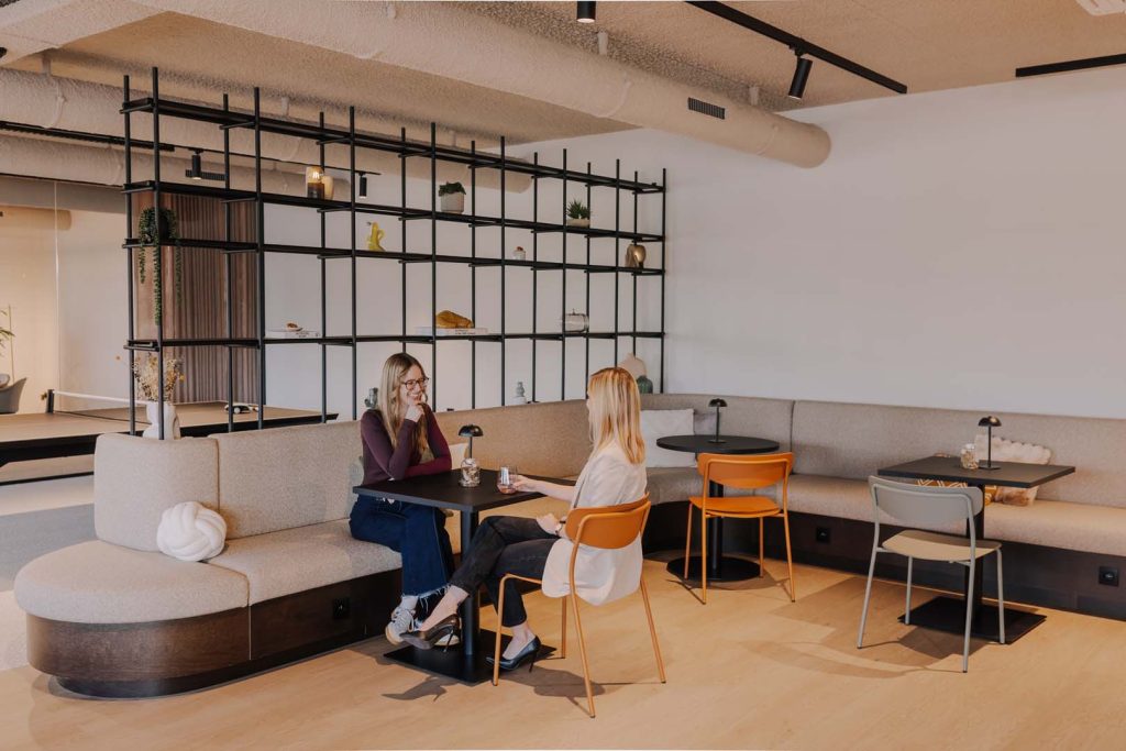 Twee vrouwen in gesprek in een informele lounge- en zithoek van een coworking space.
